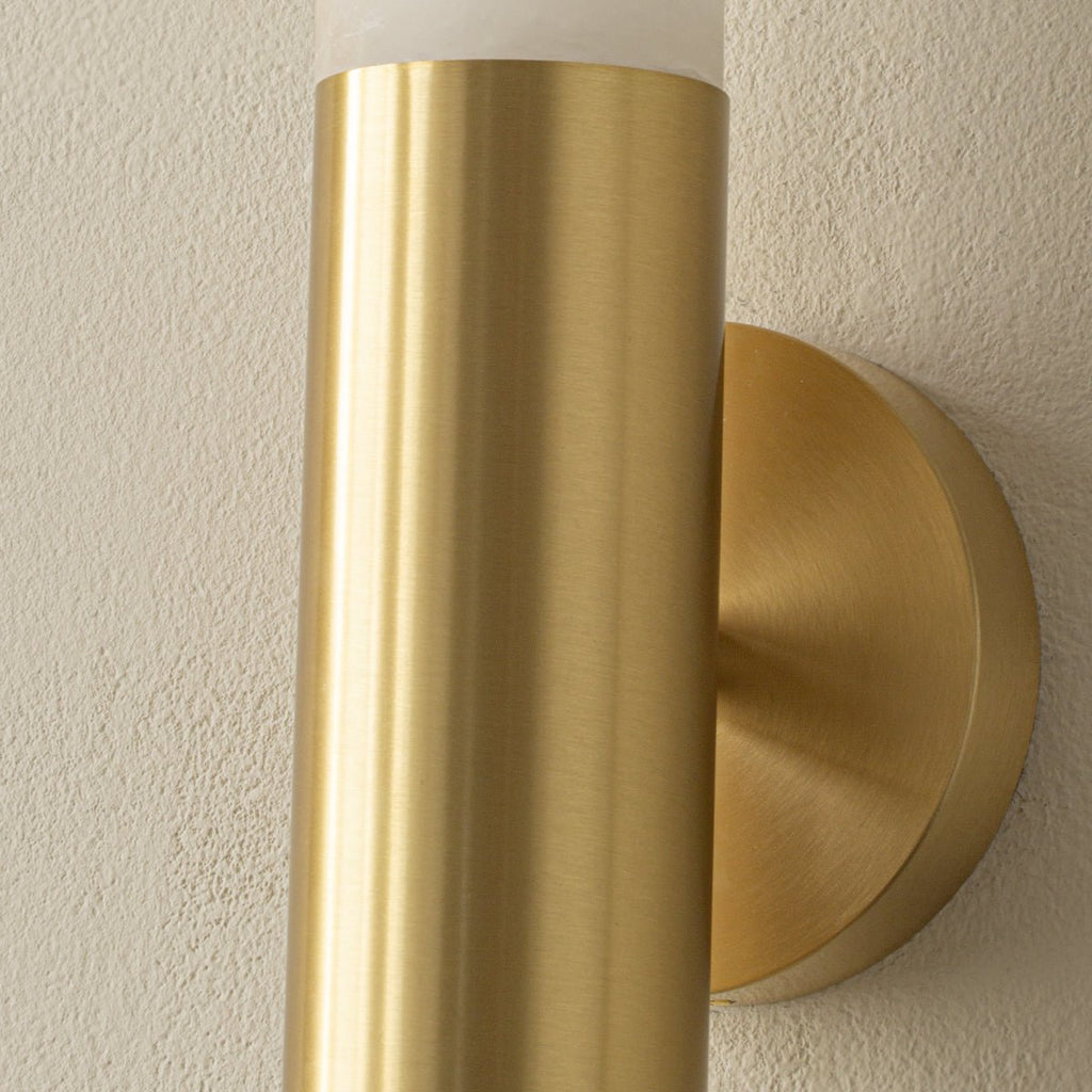 Detail of the brushed brass band and round wall plate of this Clérachic wall light, with the alabaster rising above it.
