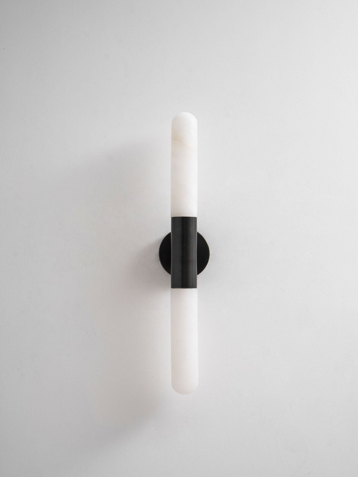 Unlit Clérachic wall light with a black band and white tube, against a plain white backdrop and soft shadow.