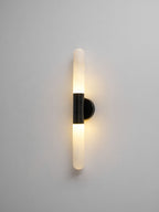 Another lit view of this Clérachic black-and-white wall light on a grey wall, showing a warm glow around both alabaster tubes.