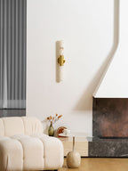 This Clérachic wall light hangs low and unlit above a cream boucle sofa and a round side table, with a stone fireplace on the right.