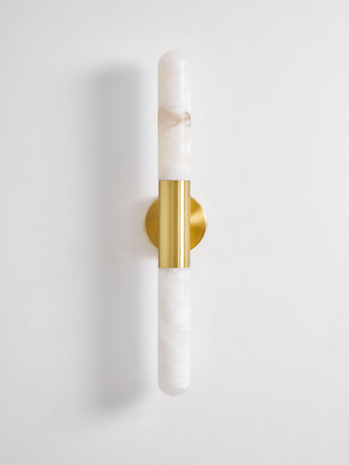 Front view of an unlit Clérachic wall light with white veined alabaster and a brass band, on a plain light wall.