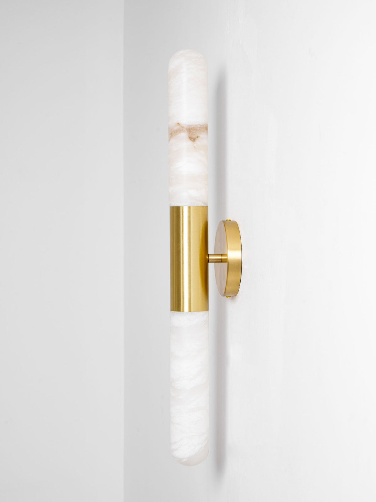 Side-on view of this Clérachic gold-and-white wall light, showing how far the brass plate holds the alabaster tubes from the wall.