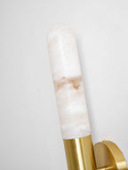 Close view of the cloudy alabaster and the brass collar at the top of this Clérachic wall light, shown at an angle against a pale wall.