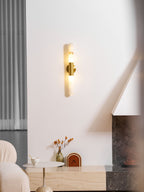 Glowing Clérachic wall sconce on a white wall, seen from a slightly different distance, with a boucle sofa and a low console beneath.