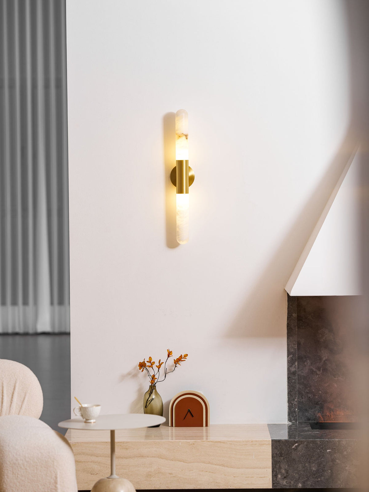 Glowing Clérachic wall sconce on a white wall, seen from a slightly different distance, with a boucle sofa and a low console beneath.