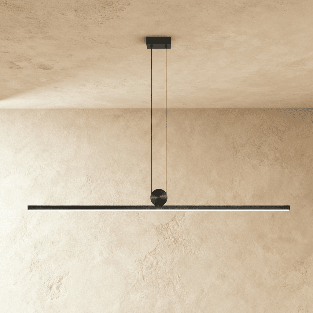 Clérachic matte black linear bar pendant, suspended on twin cables from a round ceiling canopy, glowing warm white along its length.
