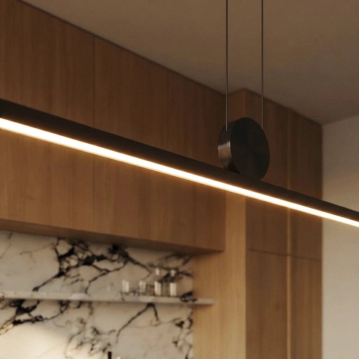 Close-up of the Clérachic pendant's round pivot disc and twin support cables, the aluminium bar glowing warm white below.