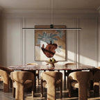 The Clérachic linear bar pendant hung low over a marble dining table, framed by panelled walls and bouclé chairs.