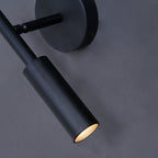 Close view of the matte black tube head and swivel joint of this Clérachic wall light, its warm light glowing at the tip.