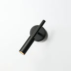 Black Clérachic wall light on a white wall with its tube head tilted across the backplate and the lit tip showing.