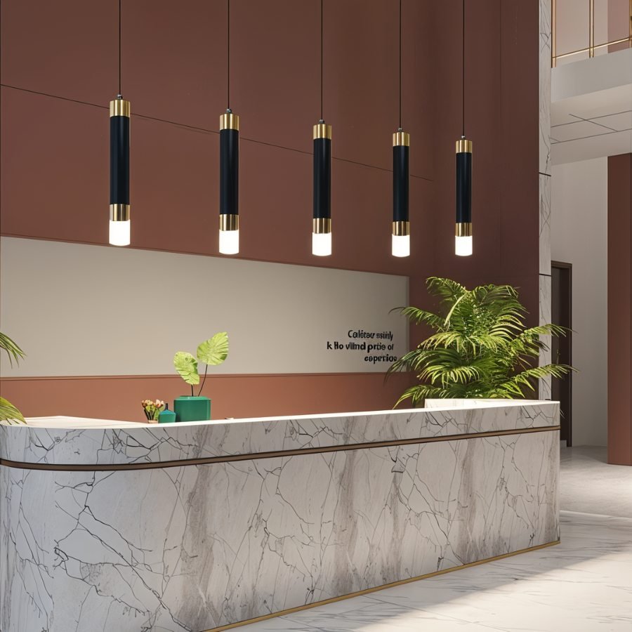 Clérachic row of five black gold-banded cylinder pendants hung above a marble reception desk in a terracotta hall.