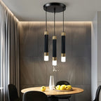 Clérachic round three-head pendant light with black gold-banded cylinders glowing above a small round dining table.