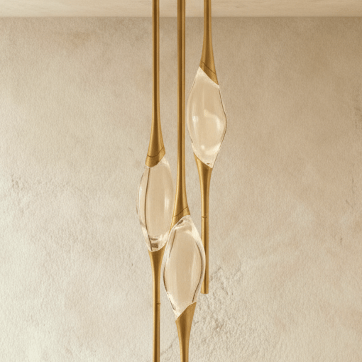 Cropped view of the Clérachic gold pendant's three clear glass teardrops held in tapered brushed brass rods.