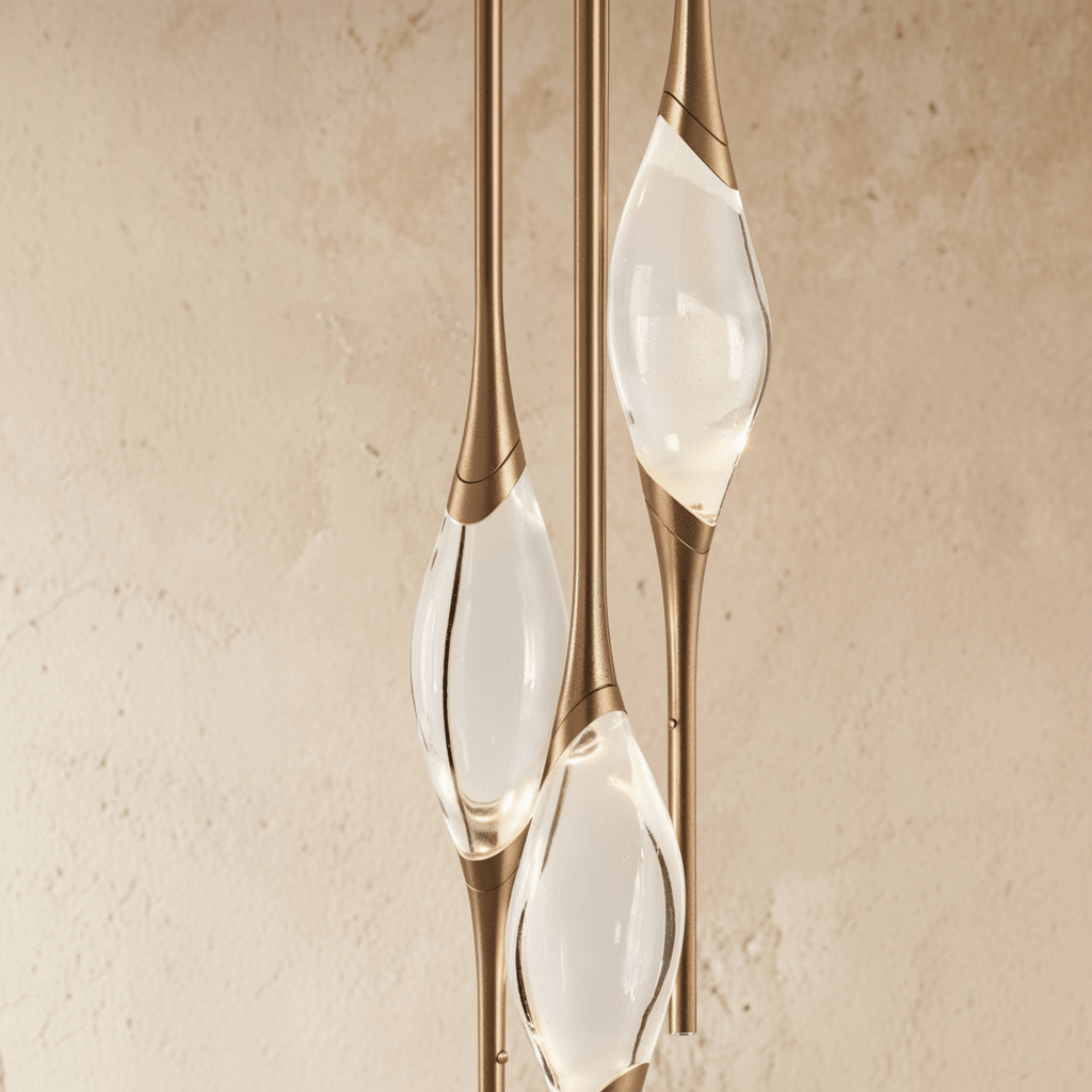 Close detail of the Clérachic gold pendant, three clear glass teardrop shades with banded brass collars at different heights.