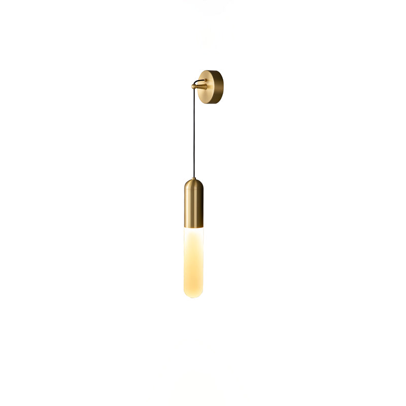 Small cut-out view of the brass Clérachic wall light on white, the slim cylinder shade lit in a warm amber tone.