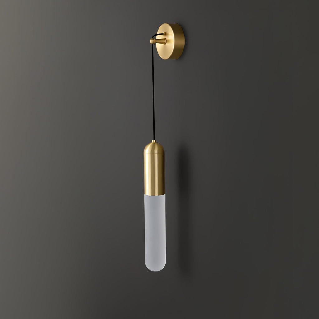 Unlit brass Clérachic wall light on a charcoal wall, the pale frosted cylinder shade hanging on a thin black cord.