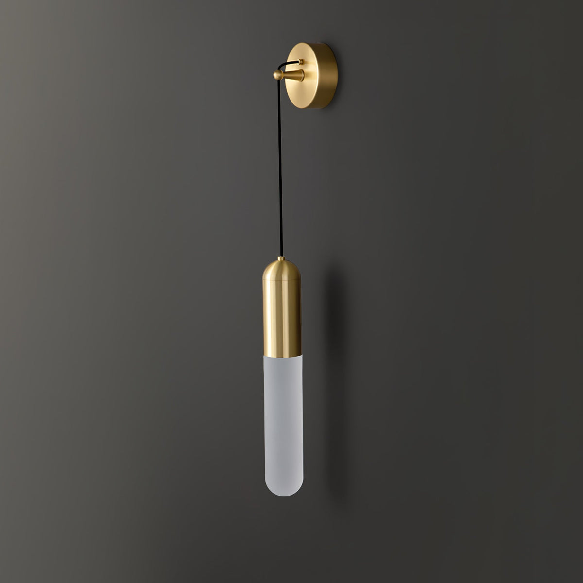 Unlit brass Clérachic wall light on a charcoal wall, the pale frosted cylinder shade hanging on a thin black cord.