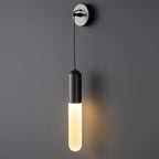 Close view of a black Clérachic wall light on a grey wall, its slim shade glowing warm below a silver-edged wall plate.