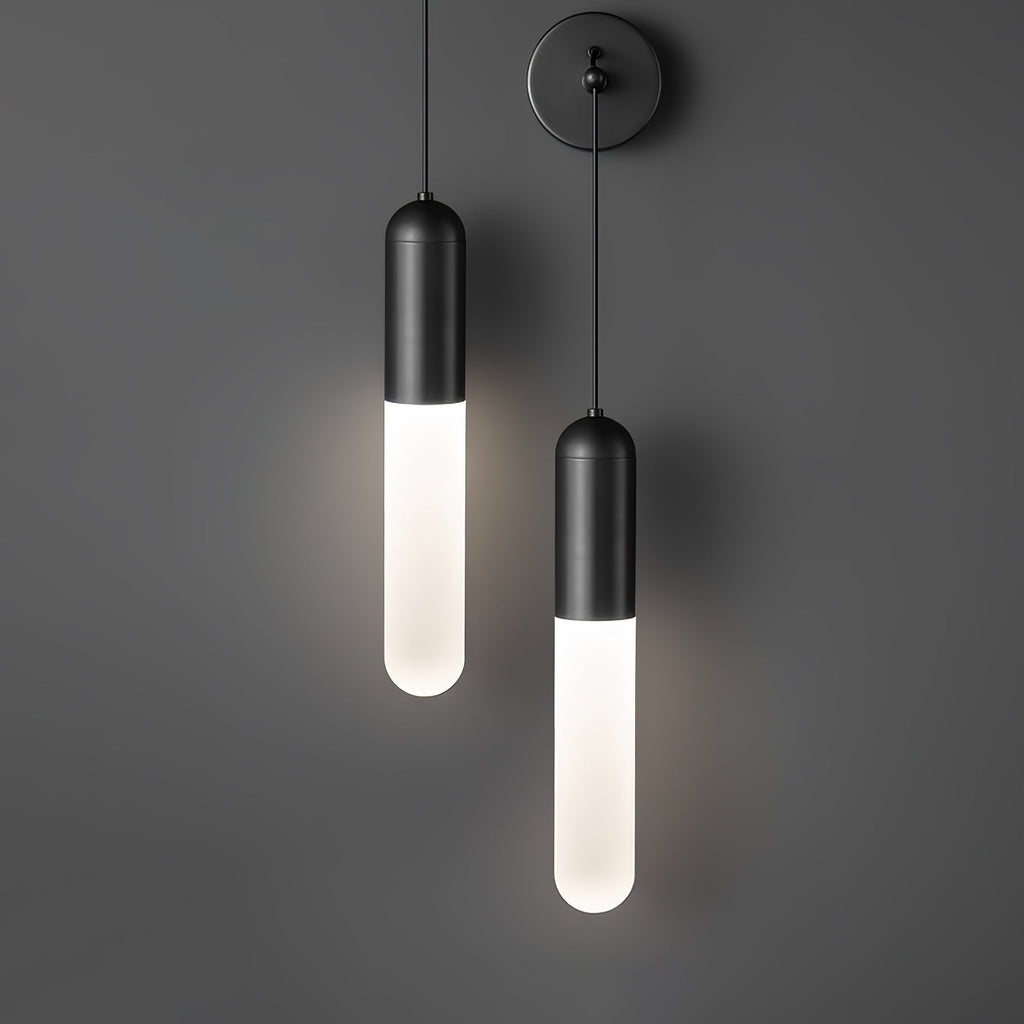 Two black Clérachic wall lights hung at different heights on a dark grey wall, both slim cylinder shades glowing white.