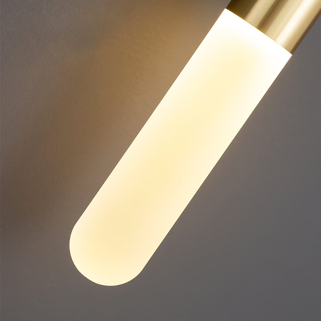 Close view of the frosted cylinder shade on this Clérachic wall light, a rounded end glowing warm below a brass cap.