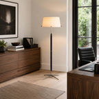This Clérachic floor lamp glows warm in a corner of a study with a walnut chest of drawers, a desk and a garden door.