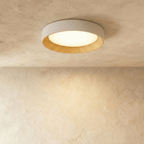 Clérachic mid-size round flush ceiling light, pale rim, ribbed light wood inner ring and a lit diffuser on plaster.