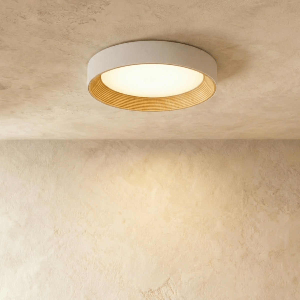 Clérachic mid-size round flush ceiling light, pale rim, ribbed light wood inner ring and a lit diffuser on plaster.