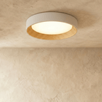 Clérachic largest round flush ceiling light with a pale rim and ribbed light wood inner ring, lit against a plaster ceiling.