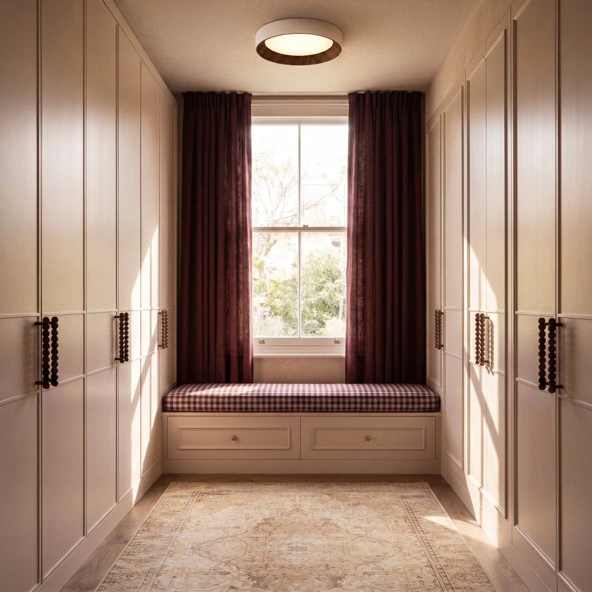 Clérachic round flush ceiling light with a walnut-tone ring centred over a window seat between tall panelled wardrobes.