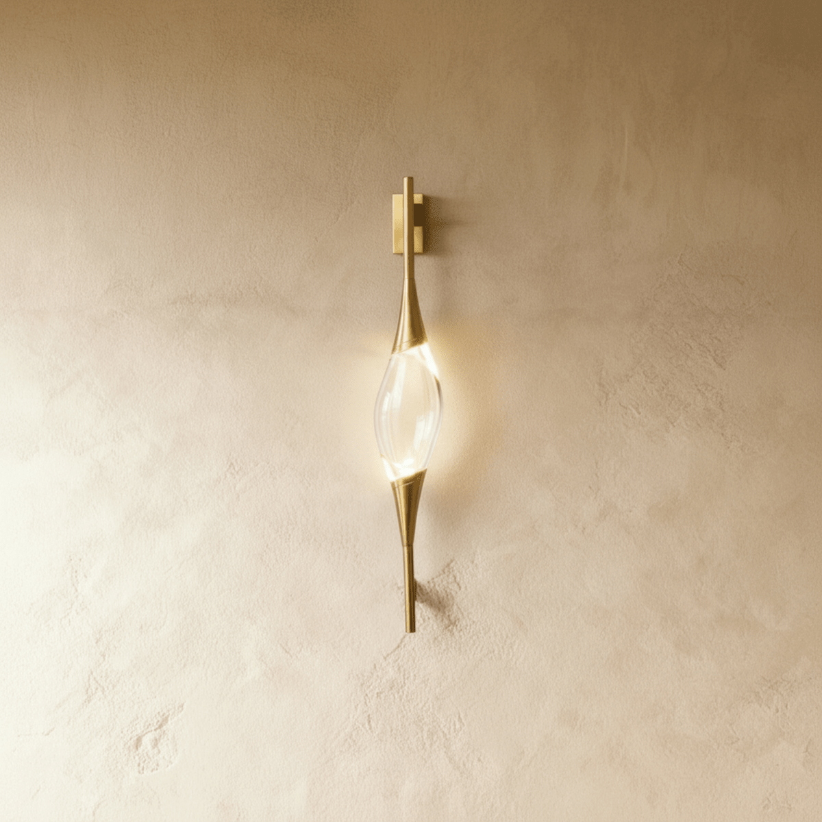 Clérachic slim gold wall light with a clear crystal centrepiece, glowing softly on a warm limewashed wall.