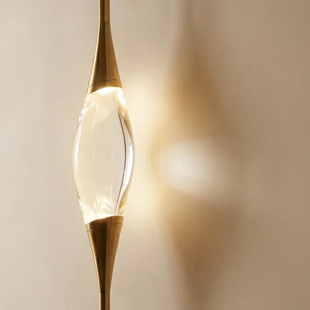 Clérachic crystal centrepiece close up, held between tapered gold metal cones and casting a soft warm glow on the wall.