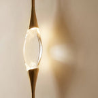 Clérachic crystal centrepiece close up, held between tapered gold metal cones and casting a soft warm glow on the wall.