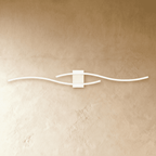 Clérachic slim white LED wall lamp with two wavy bars crossing on a square backplate, mounted on a warm limewashed wall.