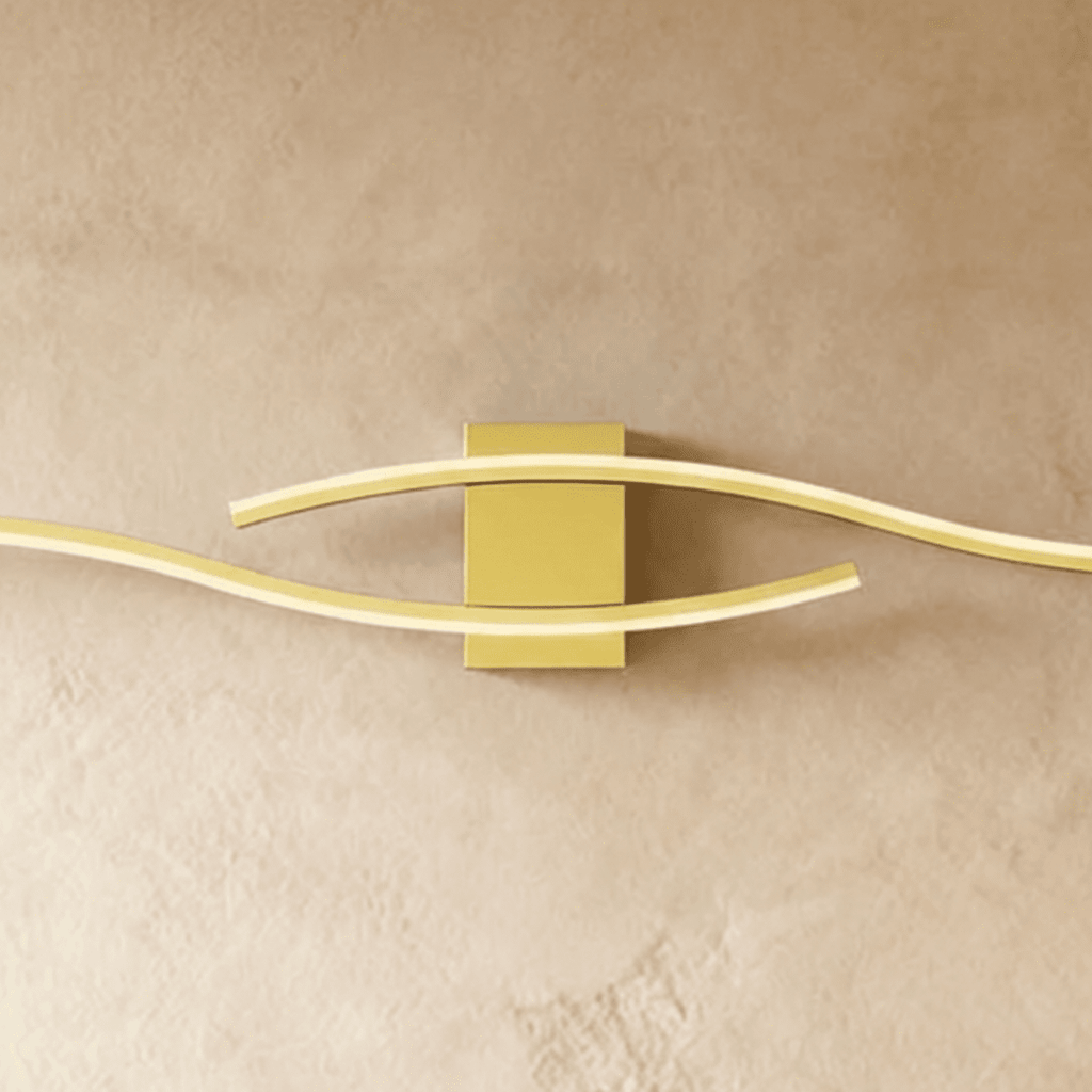 Close view of the Clérachic gold wall lamp's rectangular backplate and two softly glowing wavy diffuser bars.