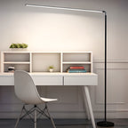 The long light bar of this Clérachic floor lamp reaches over a white desk and moulded chair, with a black pole and a round black base.