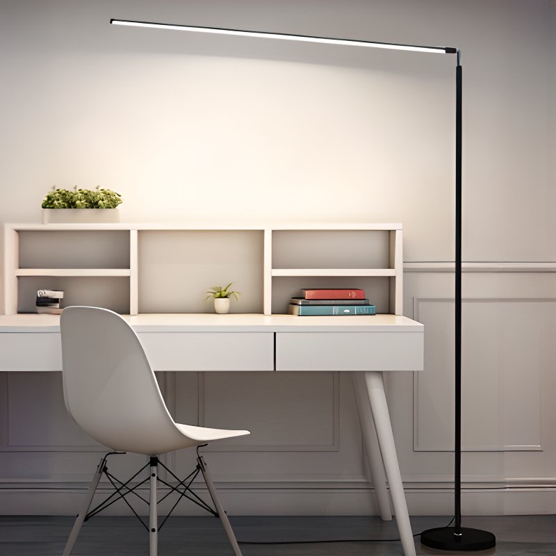 The long light bar of this Clérachic floor lamp reaches over a white desk and moulded chair, with a black pole and a round black base.