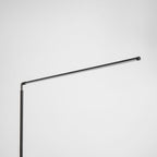 Close view of the pivot where the pole meets the long black light bar on this Clérachic floor lamp, unlit, on a pale grey backdrop.