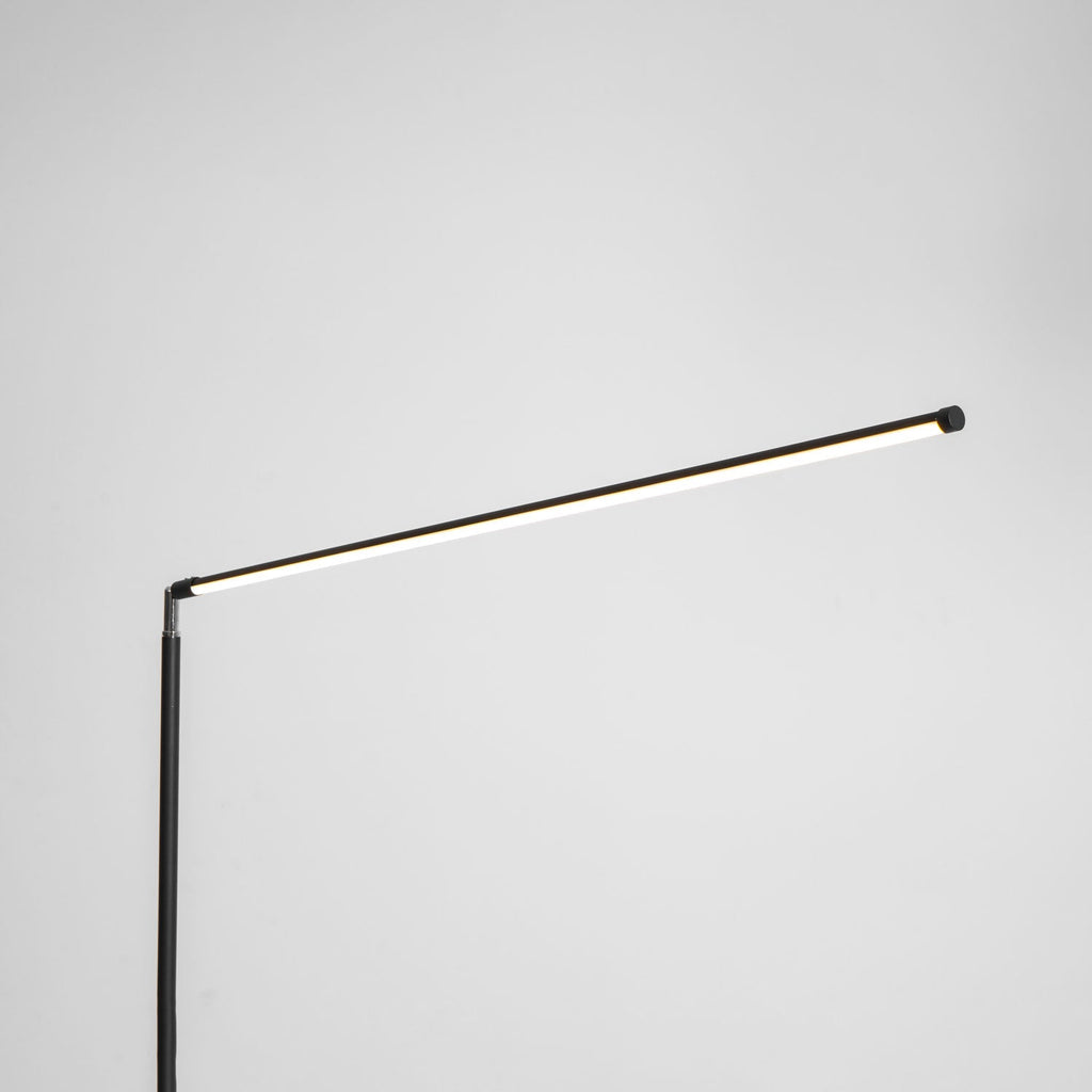 The same joint with the light bar switched on, giving a warm line of light along this Clérachic floor lamp, on a pale grey backdrop.