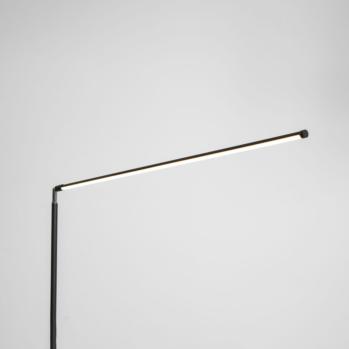 The same joint with the light bar switched on, giving a warm line of light along this Clérachic floor lamp, on a pale grey backdrop.