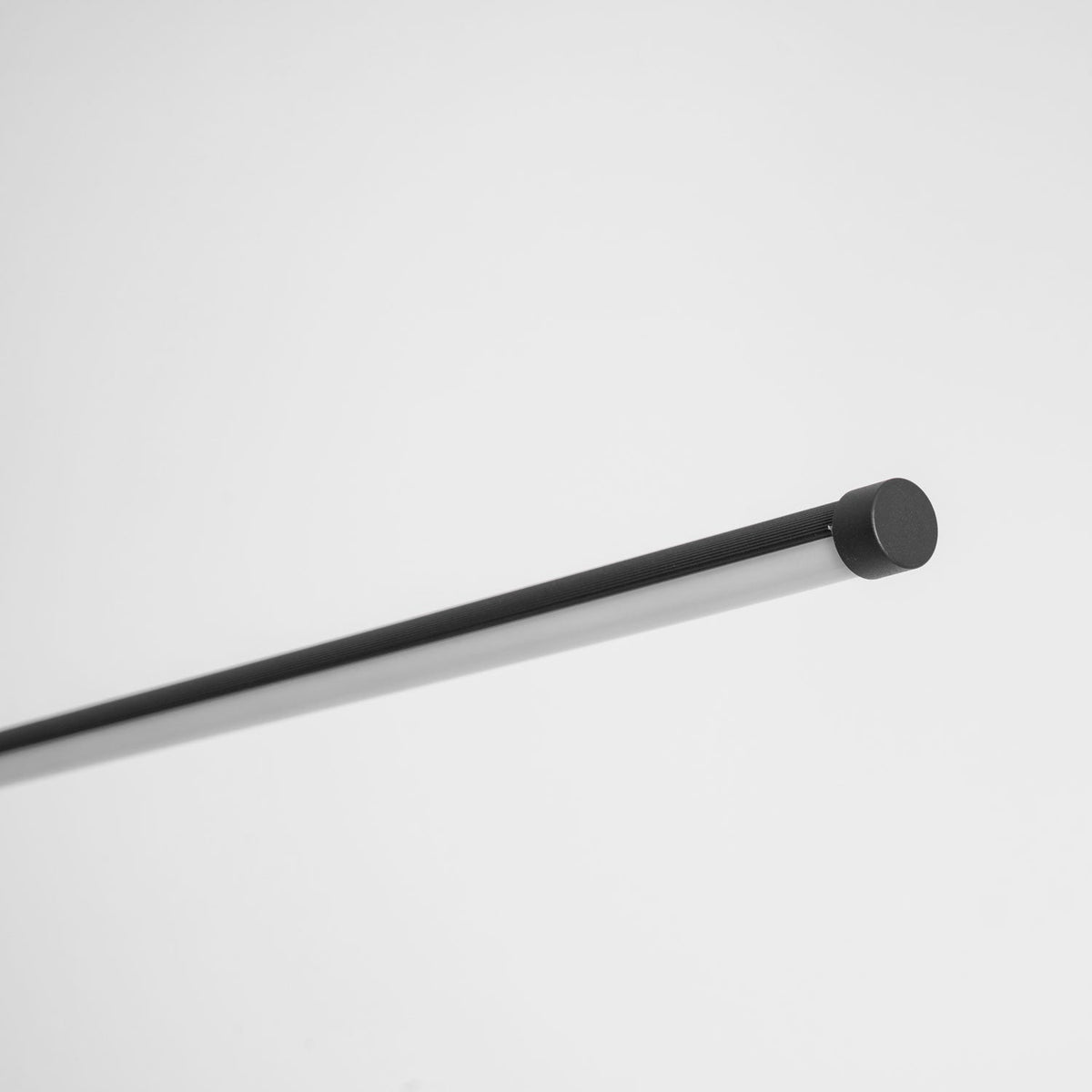 Close view of the end cap and the slim black tube of the light bar on this Clérachic floor lamp, on a pale grey backdrop.