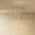 Clérachic slim white linear pendant with two suspended spotlight tubes, hanging from a rectangular canopy against a limewash wall.