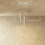 Clérachic slim white linear pendant with two suspended spotlight tubes, hanging from a rectangular canopy against a limewash wall.