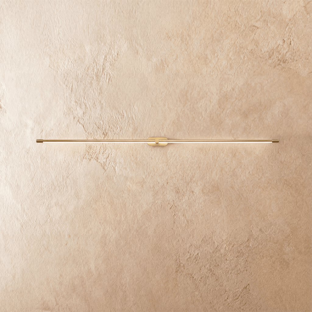 Clérachic ultra-slim linear wall light in brushed gold, with a fine line of warm light across a limewashed wall.