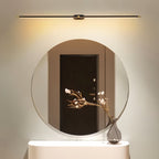 Clérachic slim black and gold bar light mounted above a large round mirror, washing the wall with soft warm light.