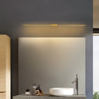 Clérachic slim gold bar light centred above a mirror on a slate-grey wall, with a white basin on a stone shelf below.
