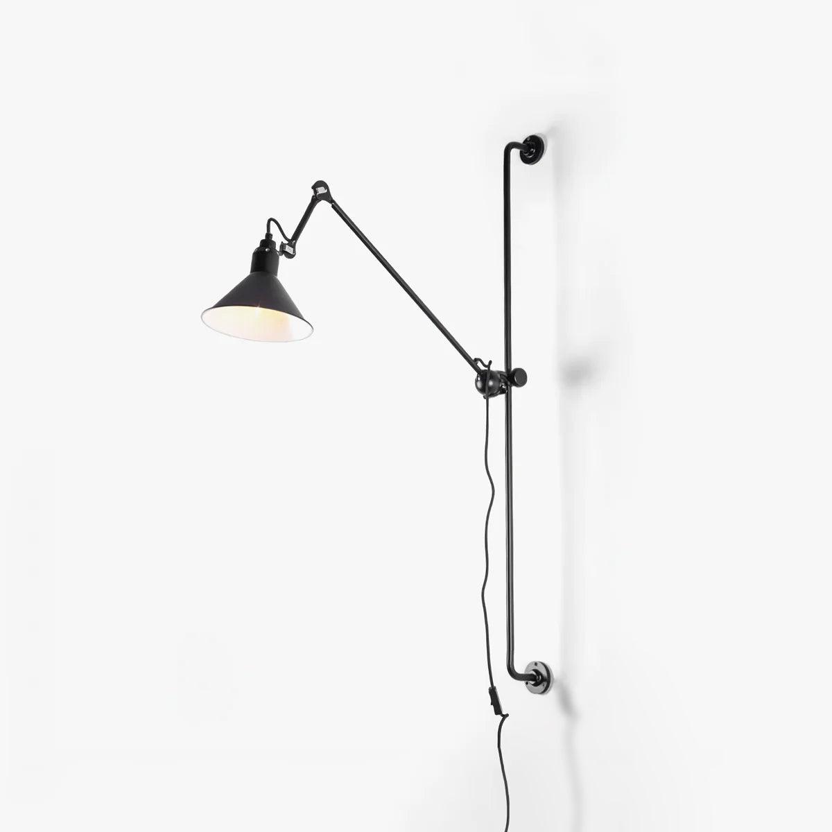 This Clérachic plug-in wall light on a plain white backdrop, a slim black vertical bar with a jointed arm and a black cone shade.