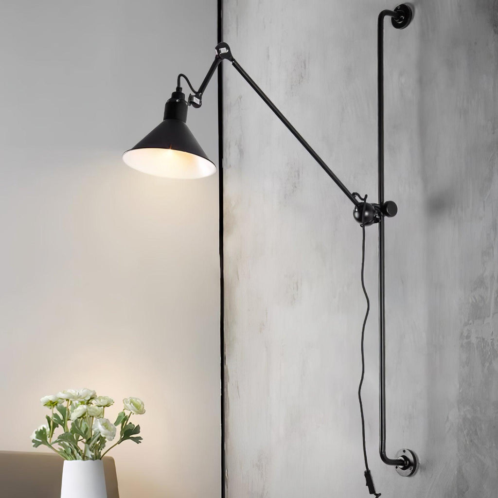 Close view of the black cone shade and jointed arm of this Clérachic wall light, lit against a concrete-look wall.