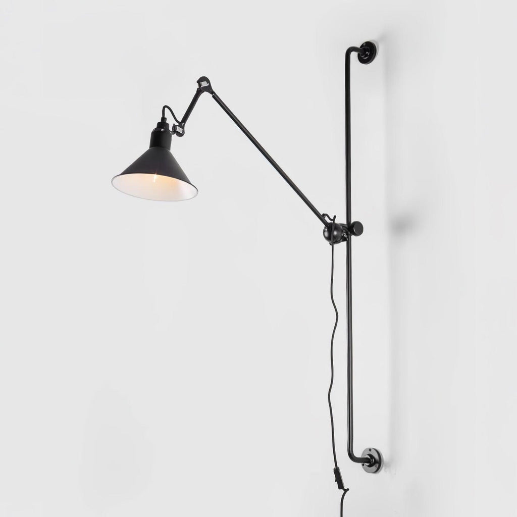 A Clérachic black cone-shade wall light on a plain white backdrop, with its white inner face glowing and its long cable hanging below.