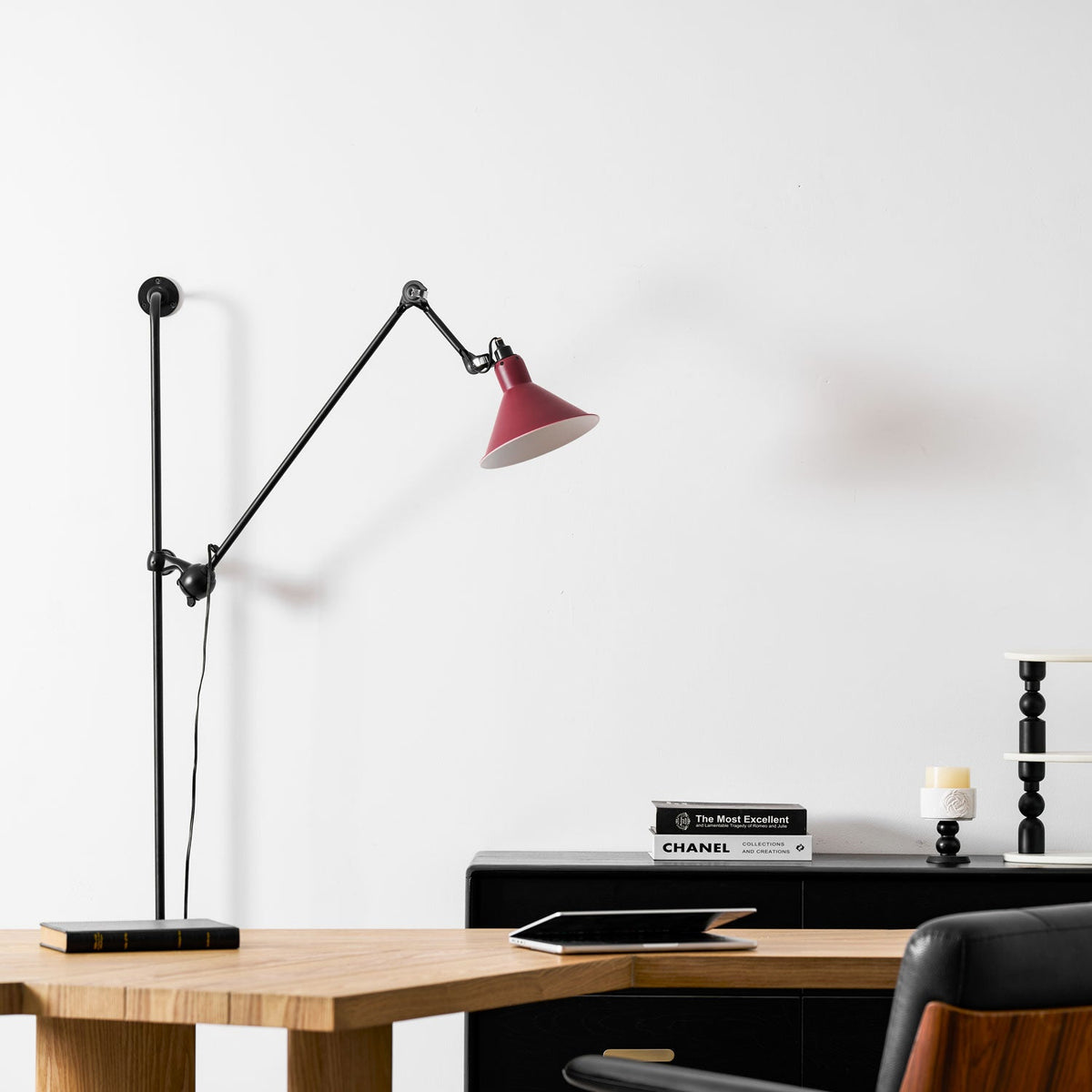 A Clérachic wall light with a deep red shade beside an arched white wall niche, above a wooden desk and a dark leather chair.