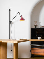 Close view of the red metal shade, small brass-coloured vent holes and black socket cap on this Clérachic wall light.